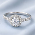 Bague argentée à pierre ronde et halo pavé